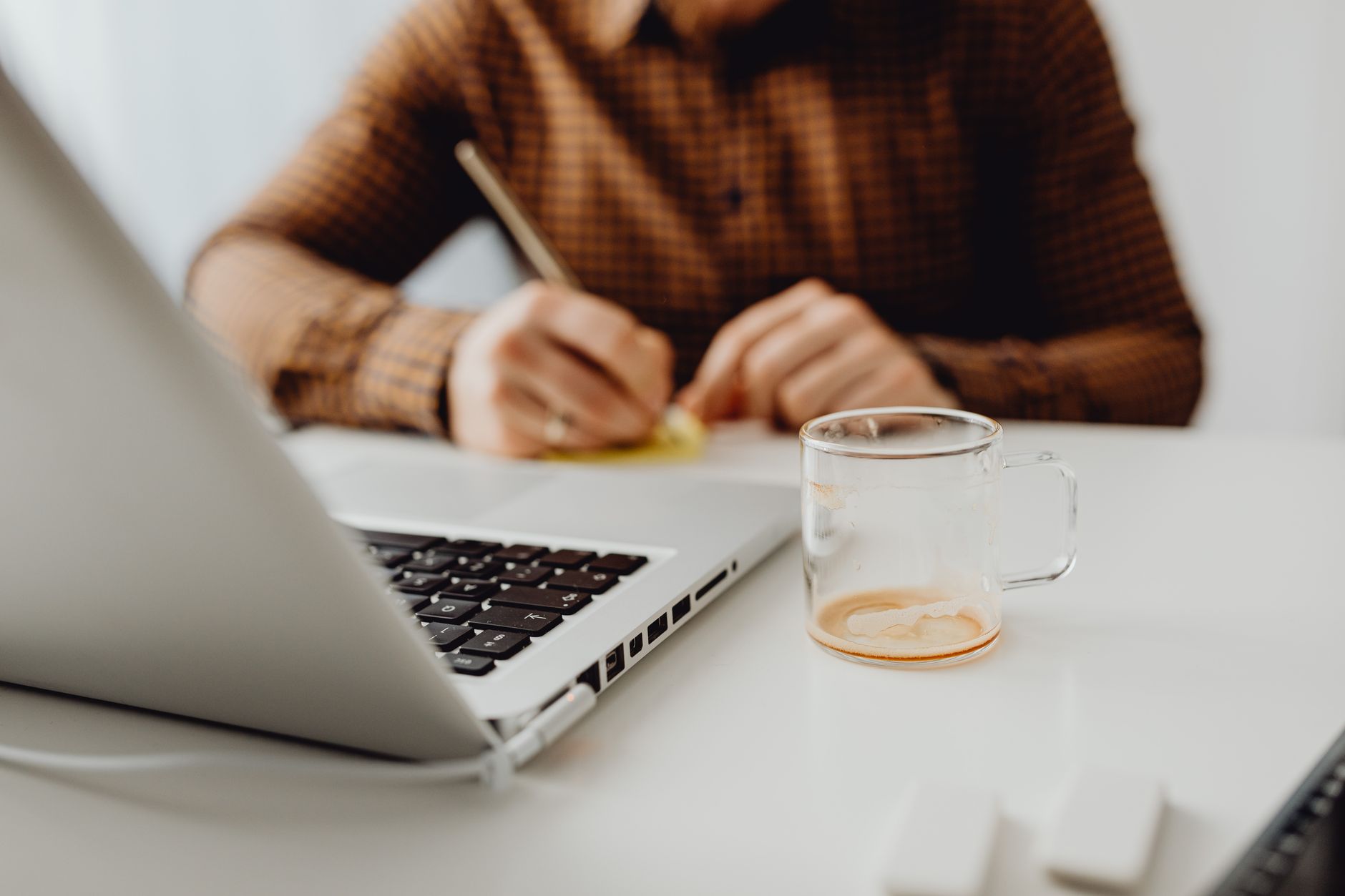 Travel consultant scheduling multi-image Facebook posts on laptop in a modern bright agency office
